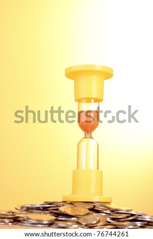Yellow hourglass with coins (Ukrainian) on yellow background
