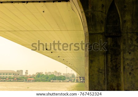 Beautiful view of under the bridge, big structure pillar and ceiling under the bridge and boat running on river at Chaophraya river Rama VIII Bridge, Bangkok, Thailand