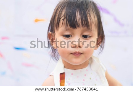Closeup face of cute asian little girl is looking to the painting brush during the art learning time, concept of art education for kid.
