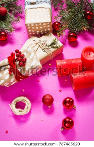 Christmas background with decorations and gift boxes on pink board.