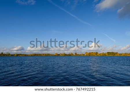 lake with water reflections in colorful autumn day with white clouds in blue sky