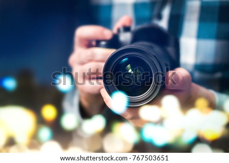 Professional photographer with camera. Man taking photos late at night. Photography and paparazzi concept. Abstract bokeh city lights.