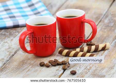 Good morning card with two red coffee mugs and crunchy wafers on rustic wooden surface

