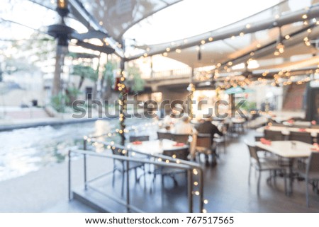 Blurred image of riverside restaurant in downtown San Antonio, Texas, USA. Riverfront popular dining places with colorful Christmas decoration along.