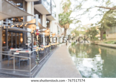 Blurred image of riverside restaurant in downtown San Antonio, Texas, USA. Riverfront popular dining places with colorful Christmas decoration along.