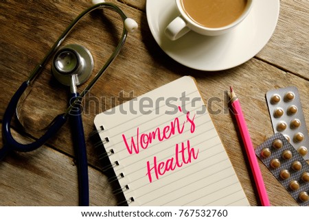 Medical concept. Top view of a cup of coffee,pink pencil,stethoscope,medicine and book written with WOMEN'S HEALTH on wooden background.