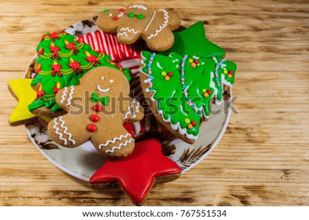 Plate with tasty festive Christmas gingerbread cookies in the shape of Christmas tree, Gingerbread man, star and Christmas stocking on wooden table