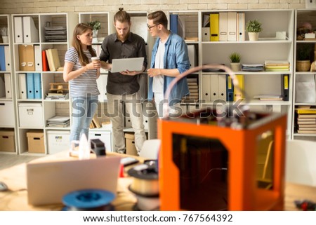 Full length portrait of three creative young people working in modern design studio using laptop and 3D printer on table in foreground, copy space