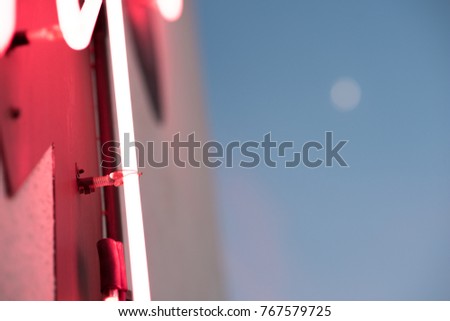 close up of the parts of a pink neon sign with a deep blue evening sky in the background.
