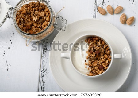 Healthy breakfast: Greek yogurt with homemade granola in a white bowl and jar with granola