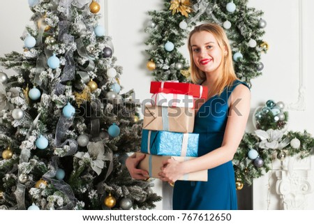 Young girl holding Christmas gift in hands and happy smiles. On the background of the Christmas tree.