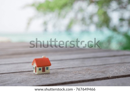 Miniature house on wooden with sea background at.Image for property real estate.