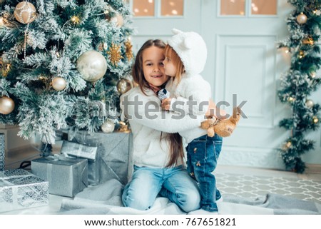 Two girls with santa hat laying in front of the christmas tree