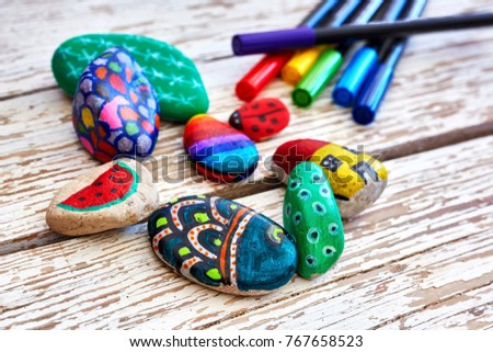 Hand-painted colorful stones and acrylic pens on a vintage textured wooden table. Stone painting. Royalty-Free Stock Photo #767658523