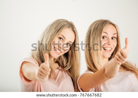 Twin sisters with thumbs up on white background
