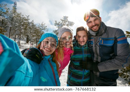 Happy family laughing and making selfie on winter ski vacation