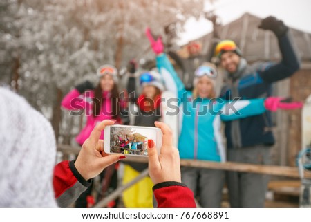 girl taking pictures of happy friends on cold holidays winter day