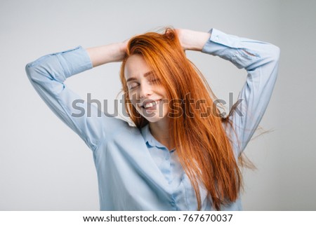 young pretty redhead girl with freckles looking at camera smiling touching hair