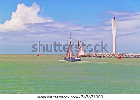 The sailing vessel goes to the sea. In the distance the leaving storm cloud, green muddy sea water after a storm. The picture is made in Ostende, Belgium, coast of the North Sea