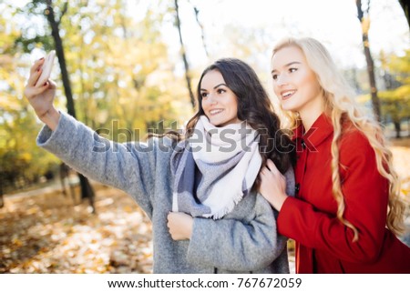 Two beautiful young woman taking selfie in autumn day