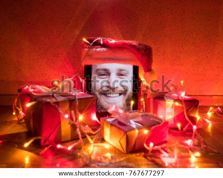 tablet with cute happy bearded male on screen and santa cap on it with Christmas attributes around