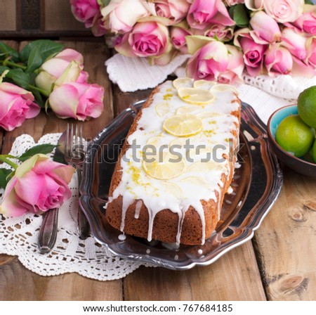 cupcake with lime and white cream on an old tray, pink roses and a wooden background