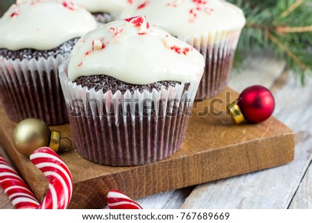 Christmas sweets and desserts, Chocolate cupcakes with candy cane crumbs, on wooden background with Christmas tree and balls, copy space