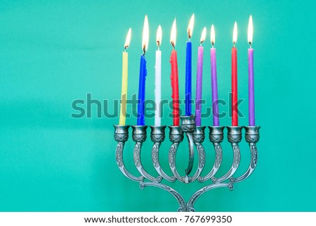 Image of jewish holiday Hanukkah on happy green background with menorah (traditional candelabra) and burning candles.