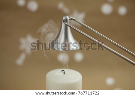 White candle, freshly extinguished. Silver candle snuffer. Christmas atmosphere.