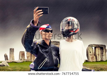 pair of dummies tourists take a selfie dressed by motorcyclists against stonehenge rocks uk. concept people travelin