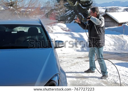 A man washes his car in the winter
