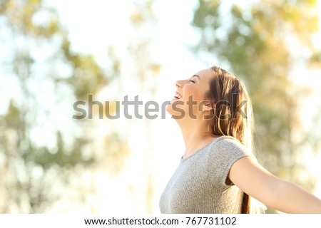 Side view portrait of a woman breathing fresh air outdoors in summer with trees and sky in the background Royalty-Free Stock Photo #767731102