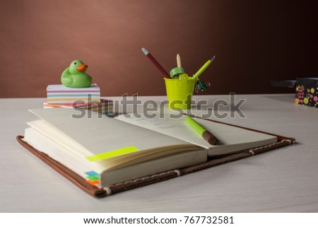 colorful stationery for business, creativity and study. on the table is an open notebook. Back is an ornamental bucket with handles and a rubber duckling