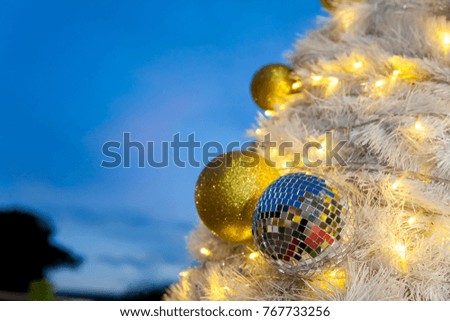 White Christmas trees are decorated with beautiful objects golden ball,  mirrored ball, light bulb and have sky in background. Waiting for the festival day at the end of the year.