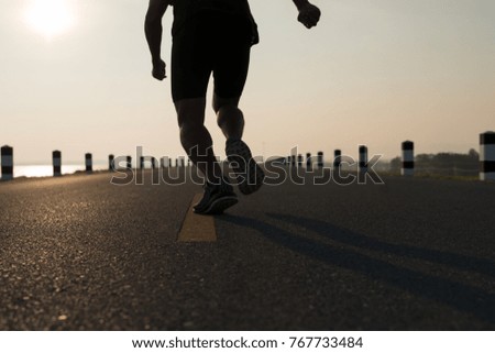 Down view of a man asia legs running in the time during sunrise on dam road exercise.Healthy lifestyle