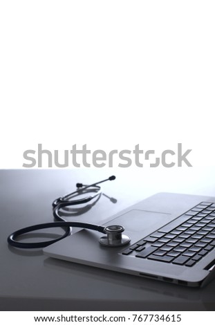 Workplace of doctor with laptop and stethoscope and notebook on white table