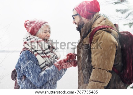 Happy couple in cozy winter clothes are having fun on the first snowfall