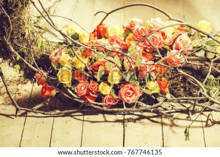 Floral arrangement with colorful rose flowers and wooden twigs on wood floor
