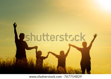Silhouette of family on the park at the sunset time. People having fun on the field. Concept of friendly family and of summer vacation