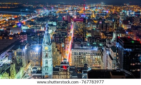 Aerial Philadelphia cityscape by night with the City Hall tower in the foreground and Ben Franklin bridge spanning Delaware river in the back