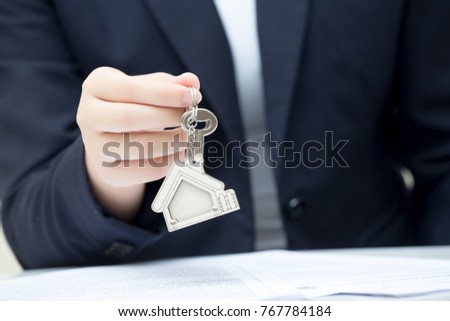 Home seller holding home key. Concept for real estate business.