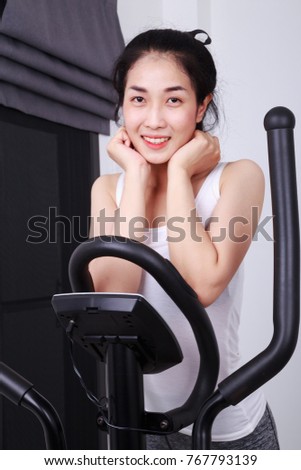 young sporty woman doing exercises with elliptical trainer
