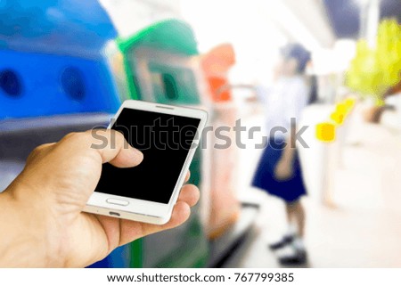 Man use mobile phone, blur image of kid is dumping garbage in the trash as background.