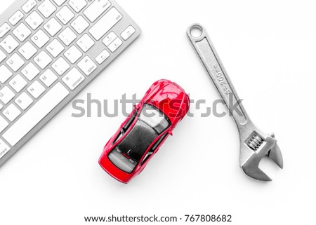 Search car service online. Wrench near car toys and keyboard on white background top view