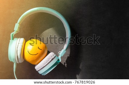 Relaxing in Summer with Music Concept, present by Orange Fruit Listening in Headphone, Happy Smiley Face Drawn on Skin