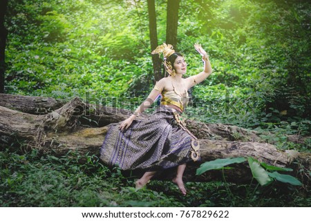 Portrait of Beautiful woman in Thai Traditional dress, Kinnara In Buddhist mythology, enjoy outdoor at forest 