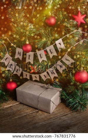 Christmas gift box on rustic wood table. Christmas lights, ball a christmas tree.
