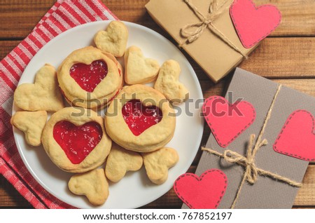 Homemade cookies in heart-shaped gifts and red paper hearts, greetings on Valentine's day, top view