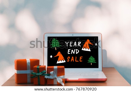 Year end sale and online shopping concept- Christmas, new year, presents box and laptop computer with advertising screen on wooden table over bokeh wall background and copy text space