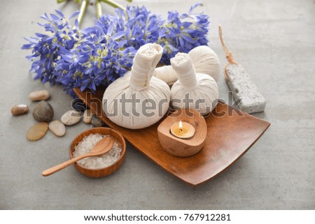 Spa setting with candle, spoon,salt in wooden bowl ,bottle oil,love flower on gray background
